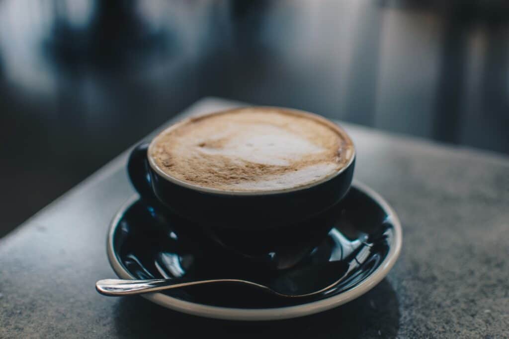 Cappuccino photo of black teacup filled with coffee on saucer