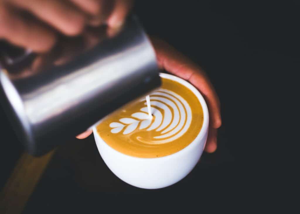 Latte person holding white ceramic mug with brown liquid